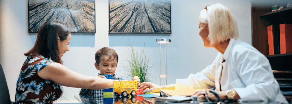 A young boy with Autism Spectrum disorder in a play therapy session with his mom and therapist.